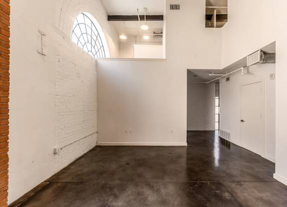3333 Elm Street Lofts studio with spacious interiors, brick accent walls, and arched window at Deep Ellum Lofts in Dallas, TX