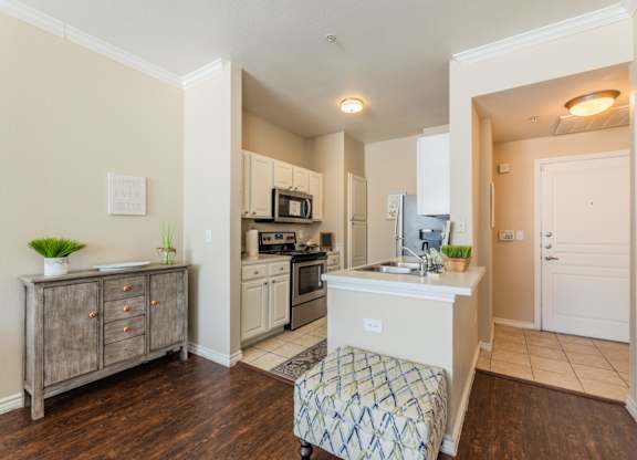 Model apartment kitchen area with short stool and wood-like flooring at Encore at Buckingham apartments in Richardson, TX