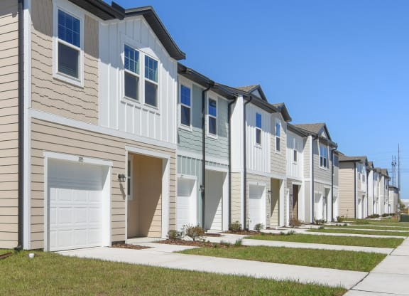 a row of townhomes with tan siding and white doors  at Beacon at Arbours, Ruskin, FL