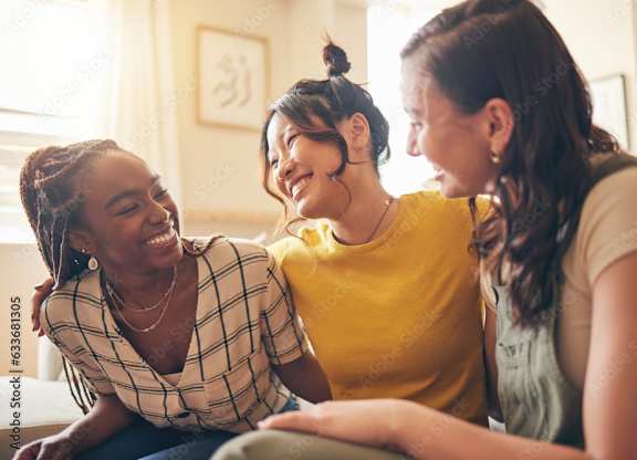 Three women are sitting closely together, sharing a moment of laughter and joy.