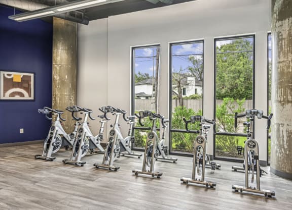 Spin bike area with large windows and mirrored wall at Allusion at West University apartments in Houston, TX
