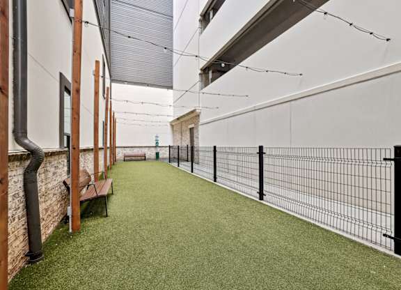 An enclosed dog park with benches, a trash can, and decorative lights at Alastair at Aria Village Apartments in Sandy Springs, GA