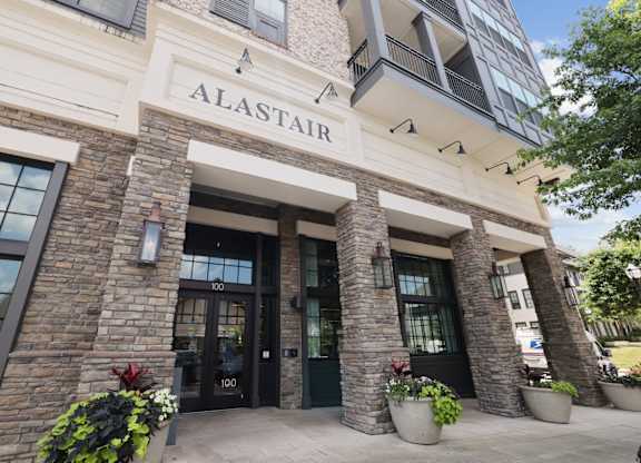 The Alastair at Aria Village leasing office entrance with stone brick pillars and potted flowers in Sandy Springs, GA