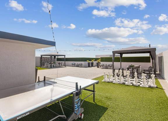 A white table tennis table is set up on a grassy area.