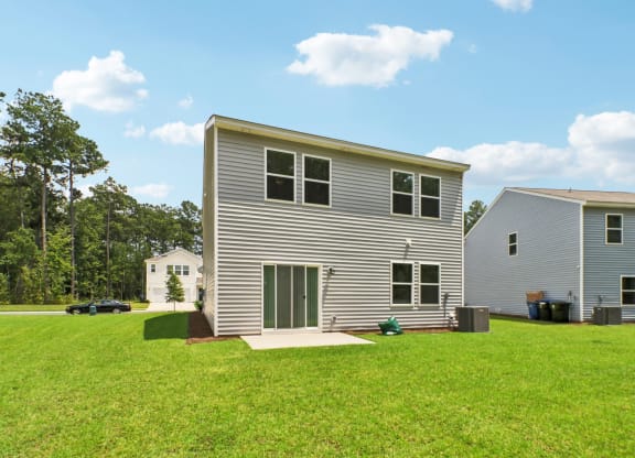 Spacious backyard with a well-maintained lawn and sliding glass doors at Beacon at Ashley River Landing in Summerville, SC