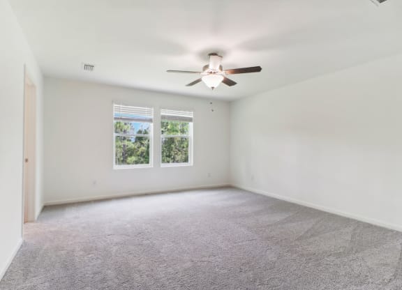 Large master bedroom with ceiling fan and carpet flooring at Beacon at Ashley River Landing in Summerville, SC