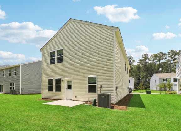 Side view of the house showcasing the expansive backyard and neighboring houses at Beacon at Ashley River Landing in Summerville, SC