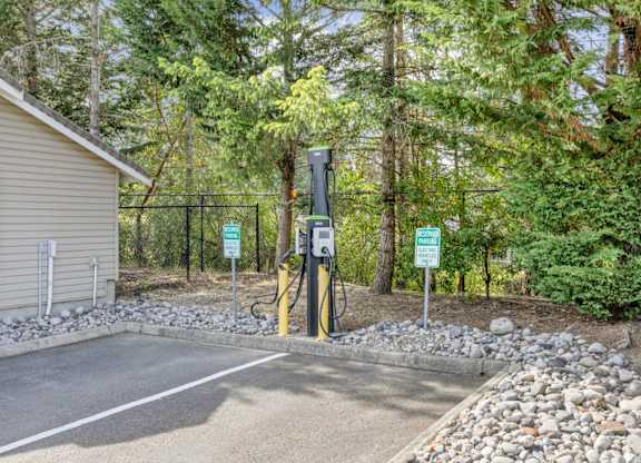 A charging station for electric vehicles with trees in the background at Abbey Rowe Apartments in Olympia, WA