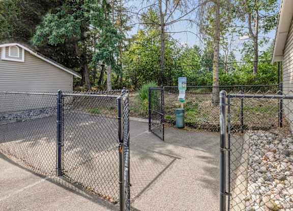 A fenced in pet area with a pet waste station at Abbey Rowe Apartments in Olympia, WA