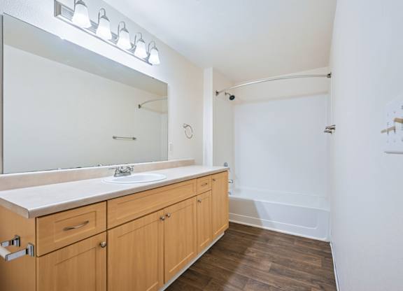 York bathroom with a bathtub and vanity sink with a large mirror and counter at Abbey Rowe Apartments in Olympia, WA