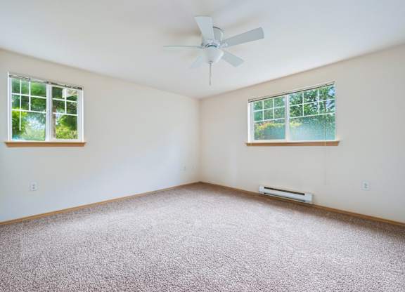 Spacious York bedroom with a carpeted floor, a ceiling fan, and two windows at Abbey Rowe Apartments in Olympia, WA