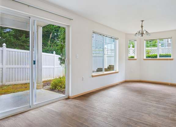 Spacious York dining room with wood floors and glass sliding doors leading to a grassy fenced in patio at Abbey Rowe Apartments in Olympia, WA