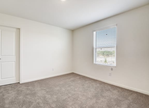 a bright bedroom with white walls and carpet