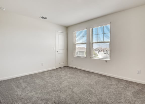 a bedroom with a door and two windows