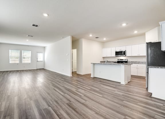 a kitchen and living room with hardwood floors and white walls
