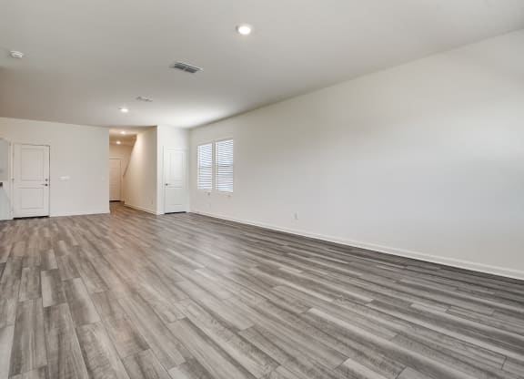 a living room with windows, hardwood floors and white walls