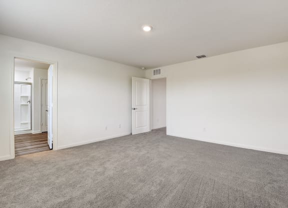a Master bedroom connected to bathroom with white walls and carpet
