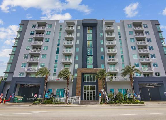 The exterior of a modern, multistory apartment building with a blue sky and clouds in the background at Blue Lagoon 7 Apartments in Miami, FL