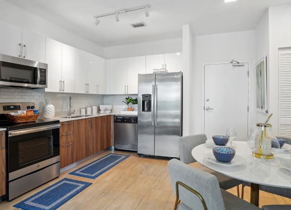 a kitchen with white cabinets and stainless steel appliances and a white table and chairs