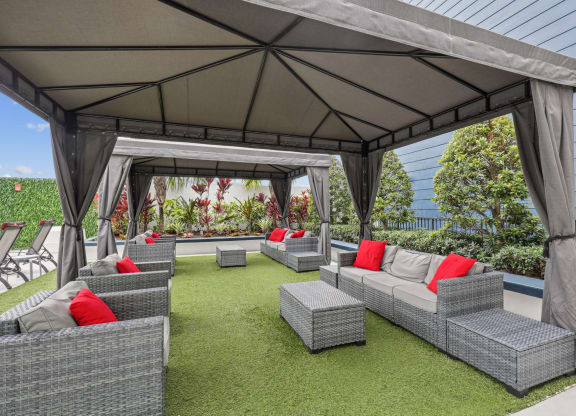 a lounge area with couches and chairs under a gazebo