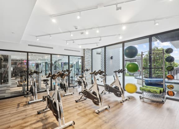 a gym with a variety of exercise equipment and large windows