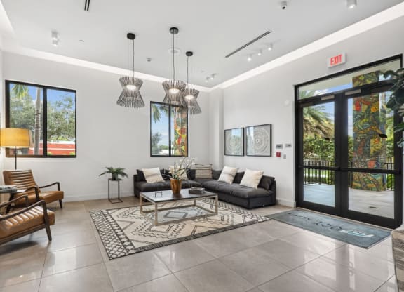 Lobby area with L sectional couch and designer lights at Bay Village 1 in Palmetto Bay, FL