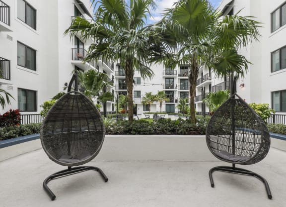 two chairs in front of an apartment building with palm trees
