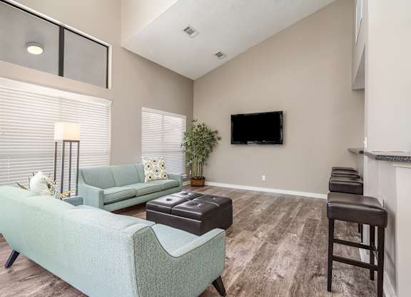 Clubhouse with a green couch and a flat screen TV mounted on the wall at Poplar Place Apartments