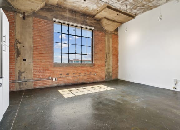 Living area in loft at Continental Lofts with brick wall and large window as well as polished concrete floor | Continental Building Lofts from Deep Ellum Lofts in Dallas, TX