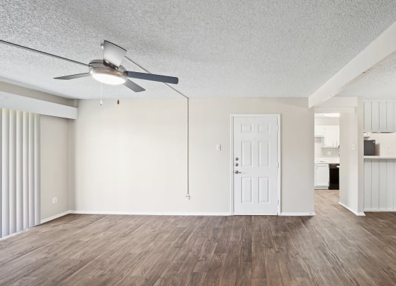 an empty living room with a ceiling fan