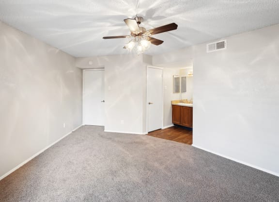 a bedroom with white walls and a ceiling fan