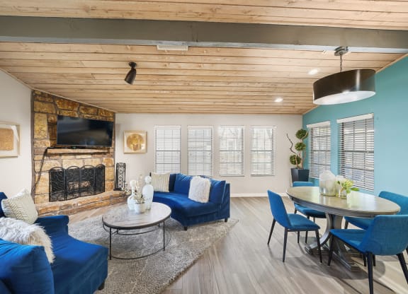 a living room with blue couches and chairs and a fireplace with a tv above it