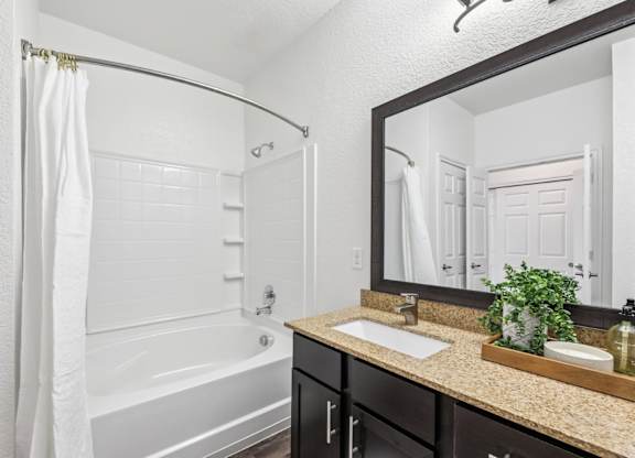 A bathroom from the B3 floorplan with a sink, mirror, and a white tub at Creekside on Parmer Lane Apartments in Austin, TX