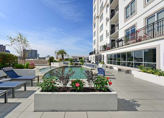 Our rooftop pool with a planter box with flowers and chairs at Dominion Post Oak apartments in Houston, TX