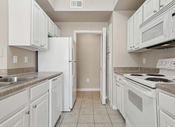 Edinburgh kitchen with white appliances and cabinets at Encore at Buckingham Apartments in Richardson, TX