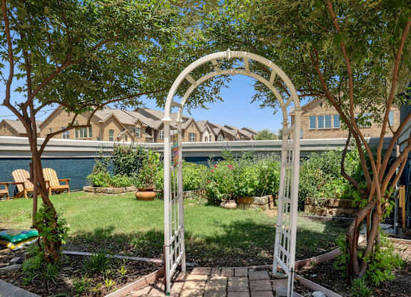 An arch entrance to a garden at Encore at Buckingham Apartments in Richardson, TX