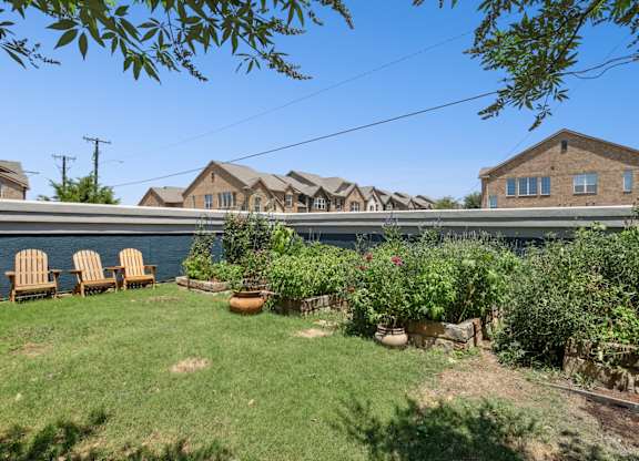 A garden with a lawn, a few chairs, and apartments in the background at Encore at Buckingham Apartments in Richardson, TX