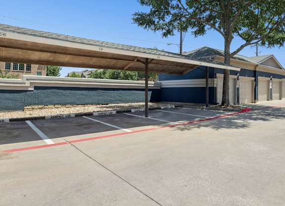 Reserved resident parking spots for compact cars with garages in the background at Encore at Buckingham Apartments in Richardson, TX