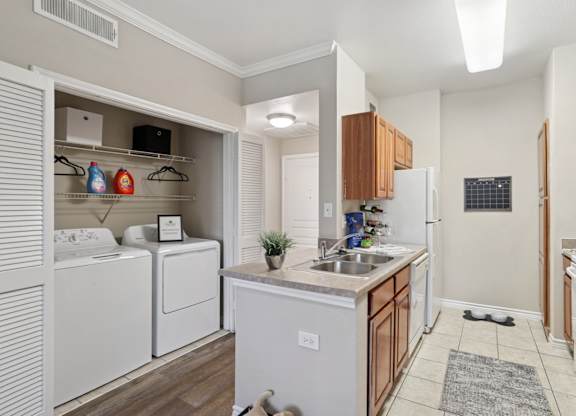 Windsor kitchen with a washer and dryer closet and white kitchen appliances at Encore at Buckingham Apartments in Richardson, TX