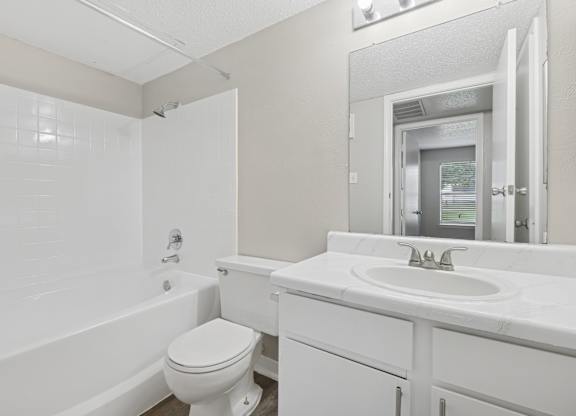 A white bathroom with a toilet, sink, and bathtub.