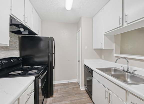 A kitchen with black appliances and white cabinets.