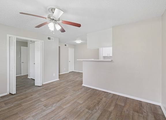 A room with a ceiling fan and wood flooring.