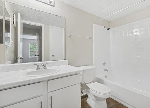A white bathroom with a toilet, sink, and bathtub.