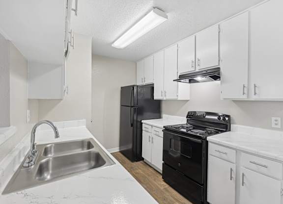 B1 kitchen with black appliances and white cabinets at Estelle Creek North Apartments in Irving, TX