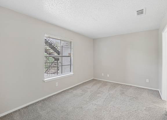 A room with a window and carpeted floor.