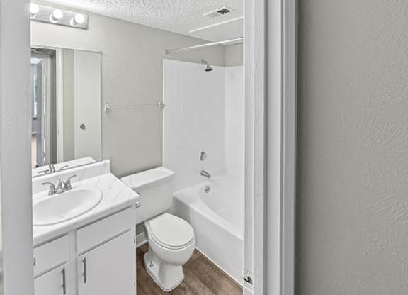 A white bathroom with a toilet, sink, and bathtub.