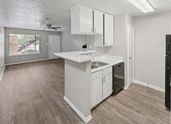 A kitchen with white cabinets and a wooden floor.