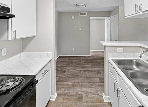 A kitchen with a stove top oven, sink, and cabinets.