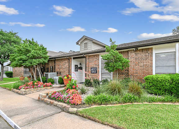 A house numbered 7023 has a driveway and a well-kept lawn.