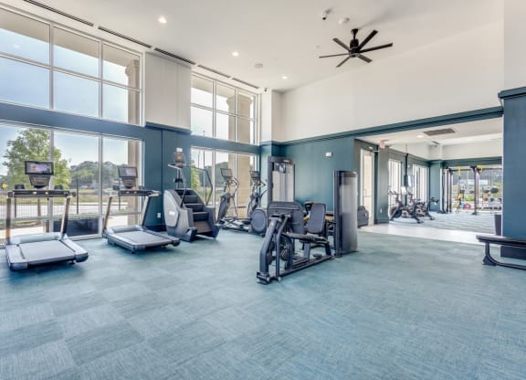 Gym cardio machines and large windows at Era Apartments in Denton, TX